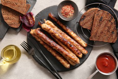 Gri arka planda ızgara sosis, sos ve ekmek.