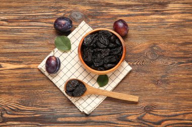 Ahşap arka planda kurutulmuş erikli kase ve kaşık.