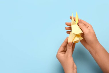 Mavi arka planda bej tavşanlı kadın eller.