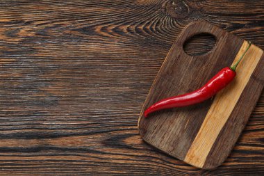 Kahverengi ahşap mutfak masasında taze biberli tahta kesme tahtası.