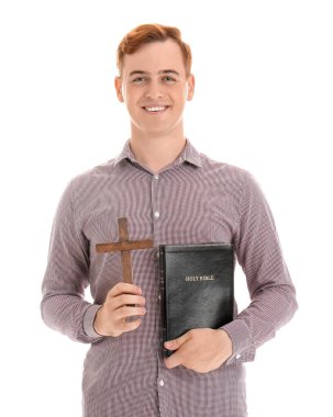 İncil 'i ve tahta haçı olan genç kızıl saçlı adam beyaz arka planda izole edilmiş.