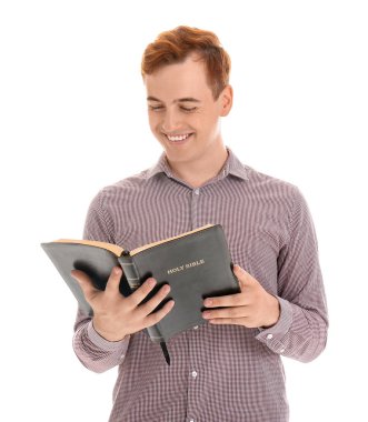 Genç kızıl saçlı adam beyaz arka planda İncil okuyor.