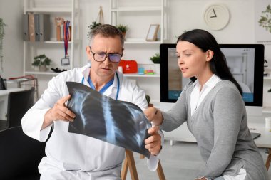 Olgun doktor, klinikteki hastaya röntgen taraması gösteriyor.