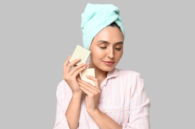 Açık arkaplanda sabun barları olan genç bir kadın, yakın plan.