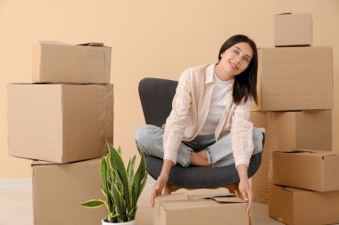 Yeni dairede koltukta oturan karton kutularla güzel genç bir kadın. Taşınma konsepti