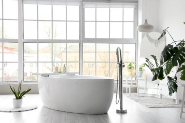 Banyonun içinde panoramik pencereli beyaz küvet.