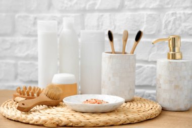 Banyoda beyaz tuğla duvarın yanında farklı banyo malzemeleri var.