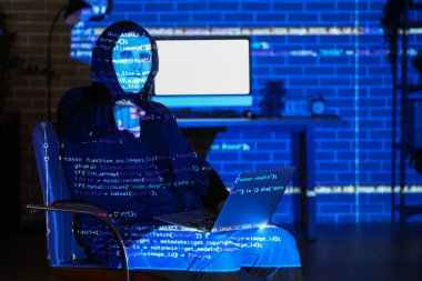 Bilgisayarı olan bir bilgisayar korsanı ve karanlık odadaki bir şeyi gösteren bir programlama kodu projeksiyonu.