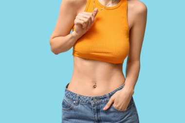 Mavi arka planda piercingli güzel genç kadın, yakın plan.