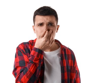 Beyaz arka plandaki kötü koku yüzünden burnunu çimdikleyen yakışıklı genç adam.