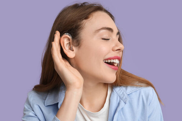 Счастливая молодая женщина со слуховым аппаратом на фоне сирени