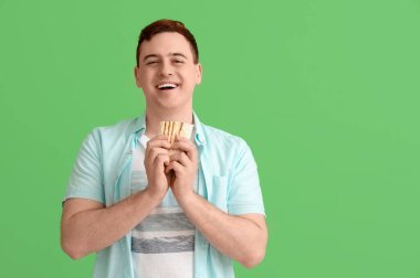 Genç mutlu adam gülümsüyor ve yeşil arka planda lezzetli bir donör kebabı tutuyor.