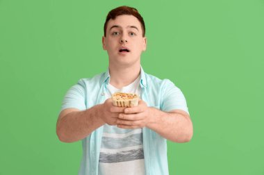 Genç adam yeşil arka planda donör kebabı tutuyor.