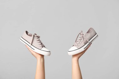 Gri arka planda şık spor ayakkabıları olan kadın elleri