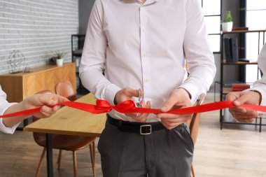 İşadamı ofiste düzenlenen açık törende kırmızı kurdele kesiyor, yakın plan.