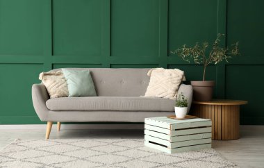 Gri kanepesi, saksısı ve kahve masası olan minimalist oturma odasının içinde.