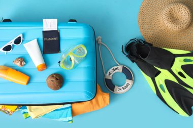 Plaj aksesuarları, kozmetik ürünleri ve pasaport içeren bavul