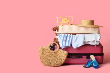 Kadın kıyafetleri, plaj aksesuarları ve renkli uçakla dolu bavullar.