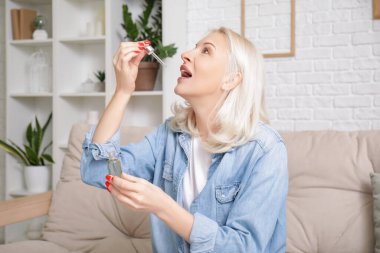 Olgun bir kadın evdeki kanepeye CBD yağı sürüyor.