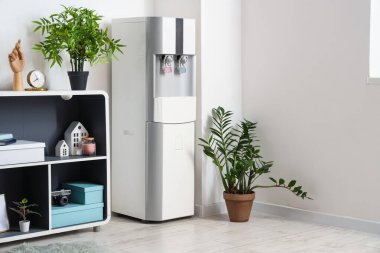 Interior of room with modern water cooler near white wall