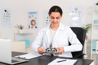 Deneme aşamasında olan kadın göz doktoru klinikte masada oturuyor.