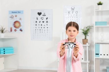 Göz kliniğinde deneme çerçevesi olan sevimli küçük bir kız.