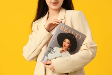 Sarı arka planda dergisi olan güzel genç bayan, yakın plan.