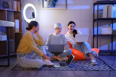 Dizüstü bilgisayarları olan kadın programcılar geceleri ofiste çalışıyor.