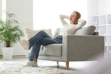 Oturma odasındaki kanepede dinlenen genç bayan.