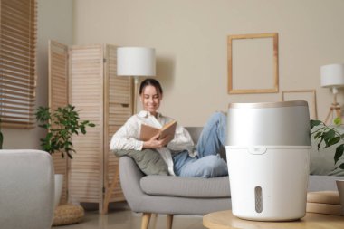 Oturma odasındaki kanepede oturan genç bayana karşı modern nemlendirici.