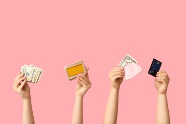 Female hands with credit cards, money and wallet on pink background