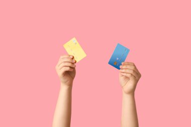 Female hands with credit cards on pink background
