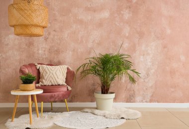 Pembe koltuklu, kahve masalı ve bej duvarlı, çiçekli şık bir oturma odası.