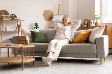 Şık oturma odasındaki kanepede dinlenen genç bayan.