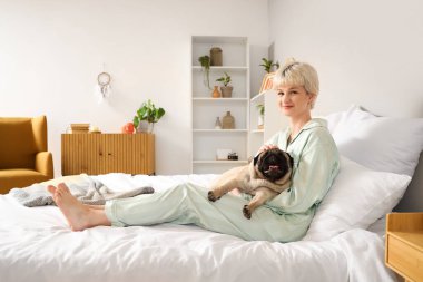 Yatak odasında köpekli genç bir kadın yatıyor.