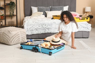 Evdeki bavullardan yaz kıyafetlerini çıkaran güzel, genç ve mutlu bir kadın.