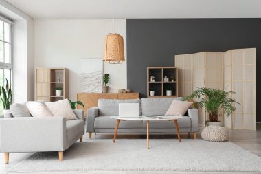 Masada gri kanepeler ve dizüstü bilgisayarlı şık bir oturma odası.