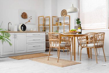 Mutfağın içinde yemek masası, sandalye, raf ünitesi ve lamba var.