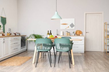 Modern mutfak, yemek masası, sandalyeler, beyaz tezgah ve lamba.