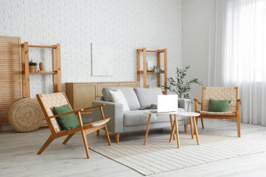 Gri kanepesi, koltuğu, sehpası, rafları ve zeytin ağacı olan güzel bir oturma odası.