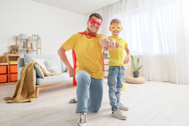 Little boy with his father in superhero costumes at home clipart