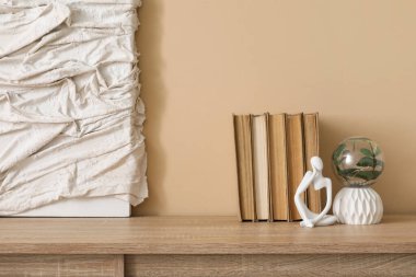 Heykel, resim ve çekmeceler üzerine kitaplar bej duvarın yanında şık bir odada, yakın plan.