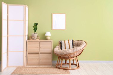 Yeşil duvarın yanında katlanan ekran, klozet ve koltuk olan odanın içi