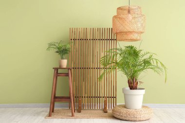 Odanın içi ahşap perdeli, sandalye ve yeşil duvarın yanındaki bitkilerle dolu.