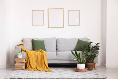 Yastıklı, ekoseli rahat bir kanepe, oturma odasındaki duvarda çiçek ve çerçeve.