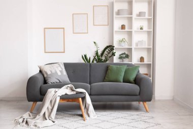 Rahat bir kanepe, yastıklar ve ekoseli, raf ünitesi ve oturma odasının duvarındaki çerçeve.