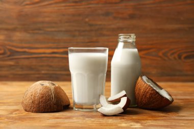 Kahverengi ahşap zemin üzerinde doğal hindistan cevizi sütü olan şişe ve cam.