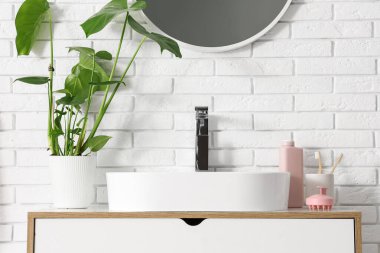 Lavabonun yanındaki çekmecelerde saç derisi masaj aletleri olan bir banyo.