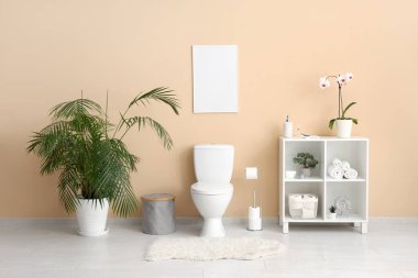 Tuvaletli modern tuvalet, orkideli raf ünitesi ve ev bitkisi.