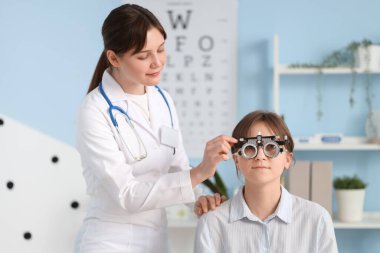 Kadın göz doktoru klinikteki hastaya deney çerçevesi takıyor.